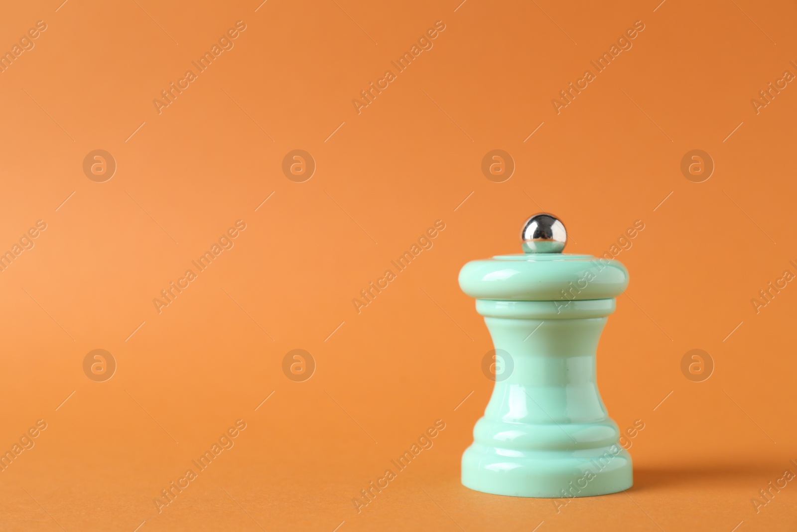 Photo of One turquoise shaker on orange background. Space for text