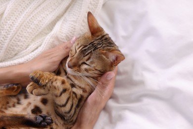 Photo of Woman with cute Bengal cat on bed at home, above view and space for text. Adorable pet