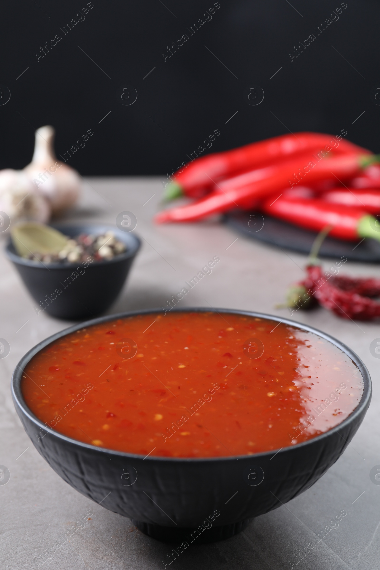 Photo of Spicy chili sauce in bowl on grey table