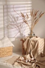 Photo of Vase with decorative dried plants and painting in stylish room interior