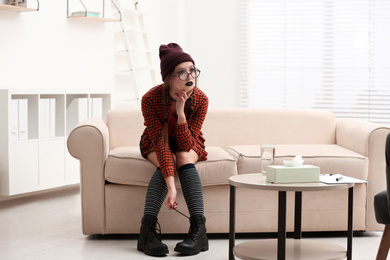 Teenage girl sitting on sofa in psychotherapist office