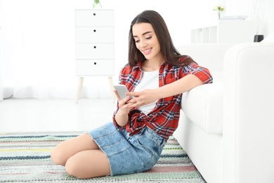 Photo of Attractive young woman using mobile phone at home