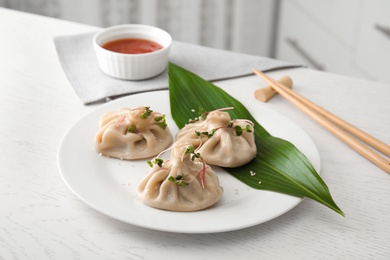 Photo of Plate with tasty baozi dumplings on white wooden table