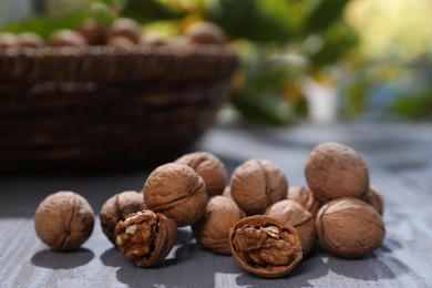 Photo of Pile of walnuts on grey wooden table outdoors. Space for text