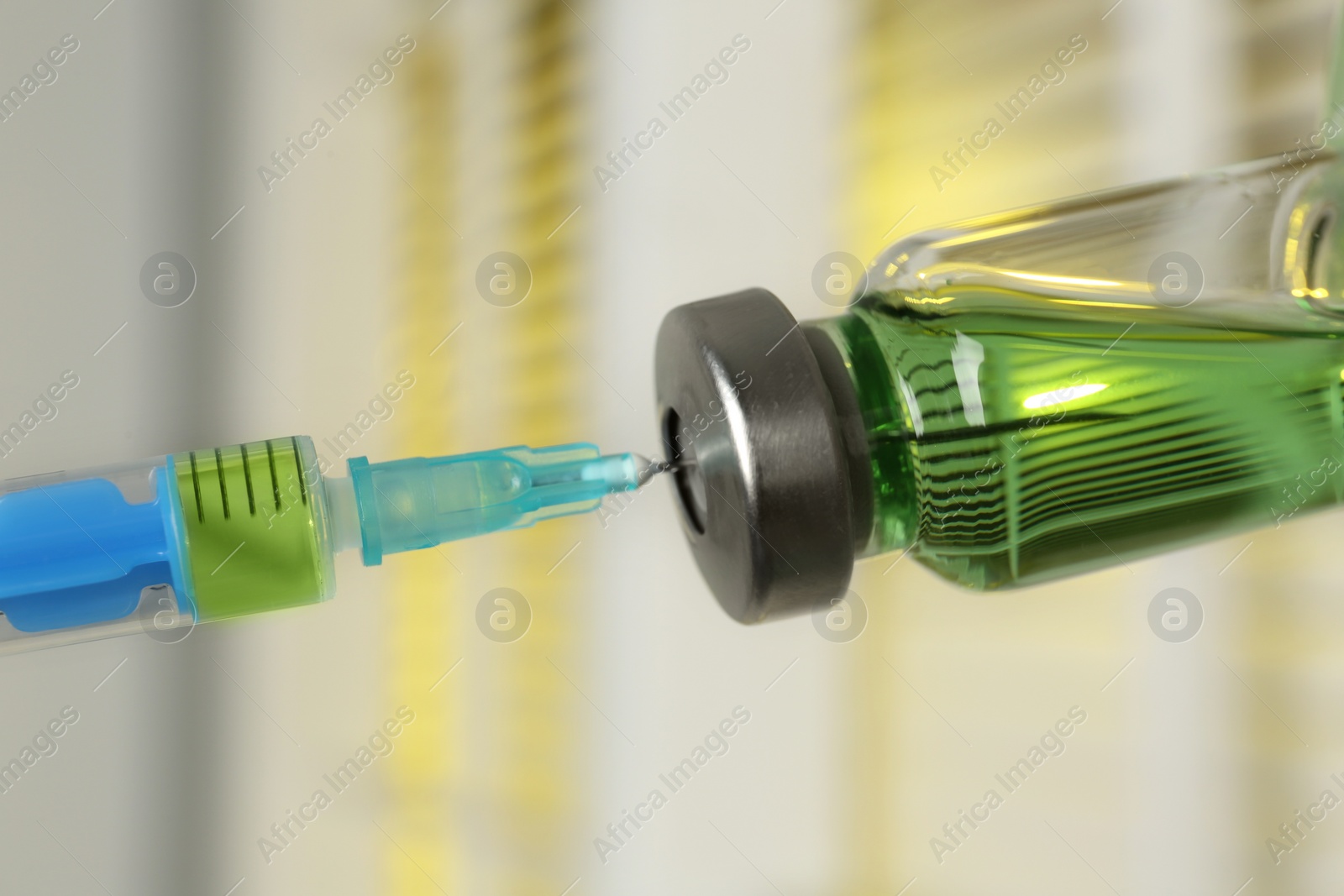 Photo of Filling syringe with medication from vial against blurred background, closeup. Vaccination and immunization