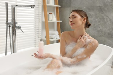 Photo of Woman taking bath with shower gel in bathroom