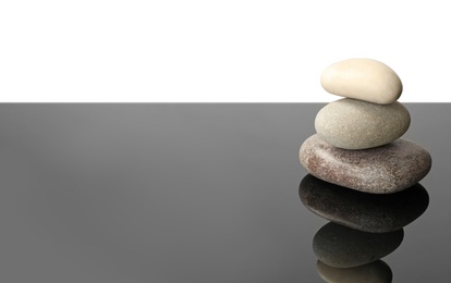 Photo of Stack of spa stones on mirror surface. Space for text