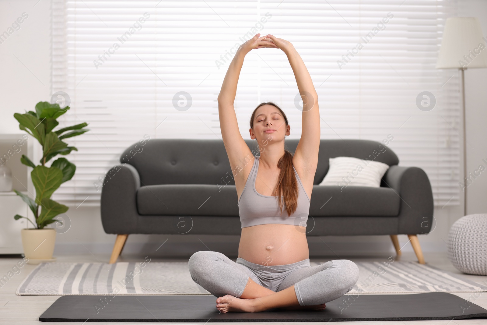 Photo of Pregnant woman doing exercises on yoga mat at home