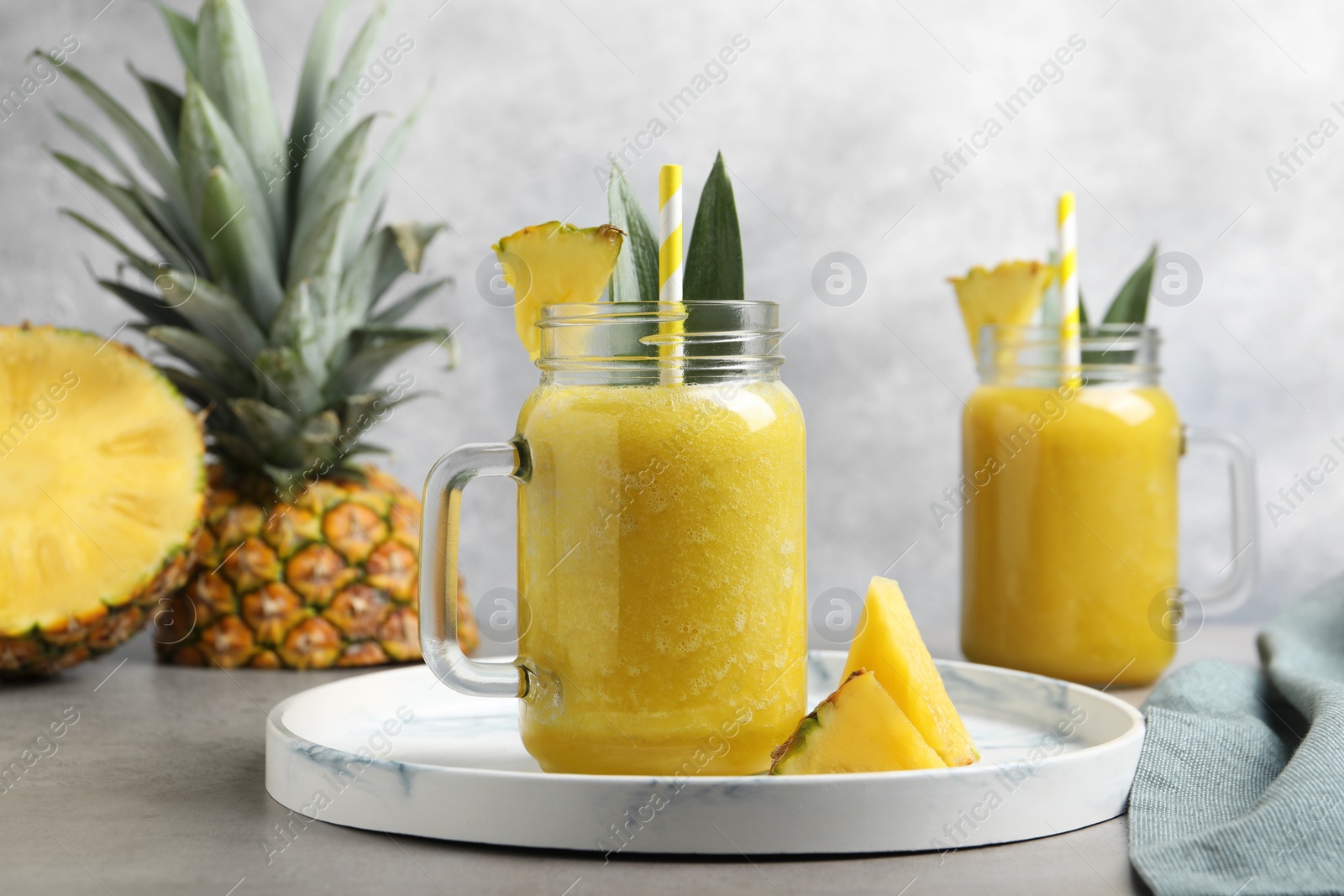 Photo of Tasty pineapple smoothie and sliced fruit on light grey table