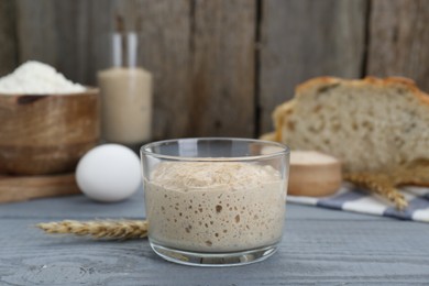 Photo of Glass jar with sourdough on grey wooden table