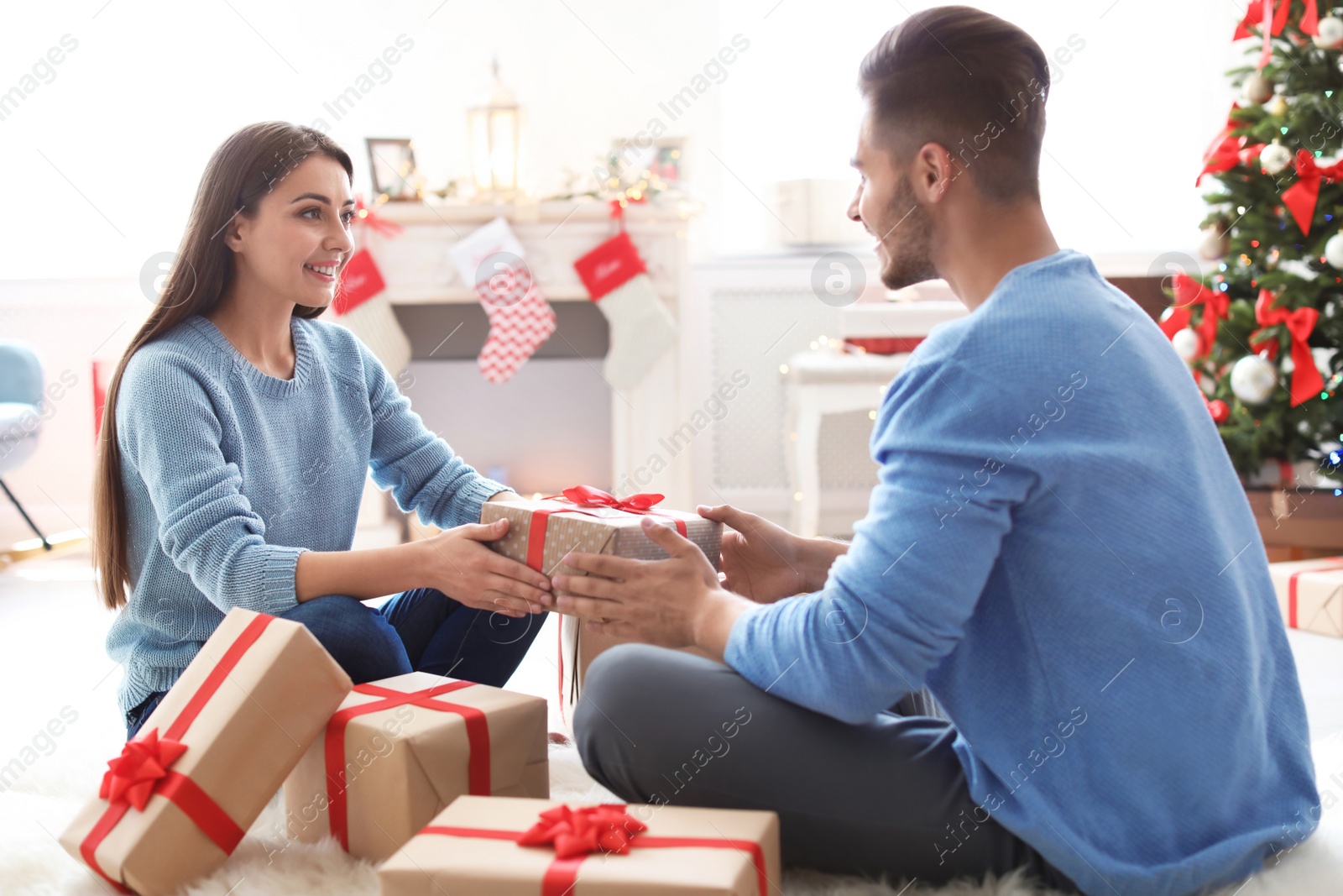 Photo of Young couple with Christmas gift at home