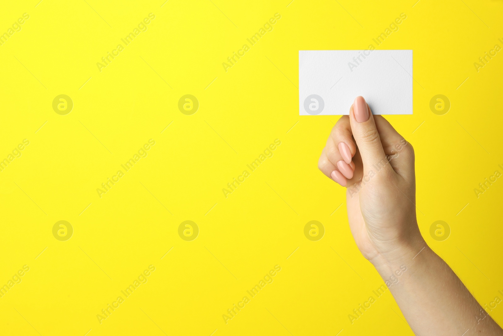 Photo of Woman holding blank business card on yellow background, closeup. Mockup for design