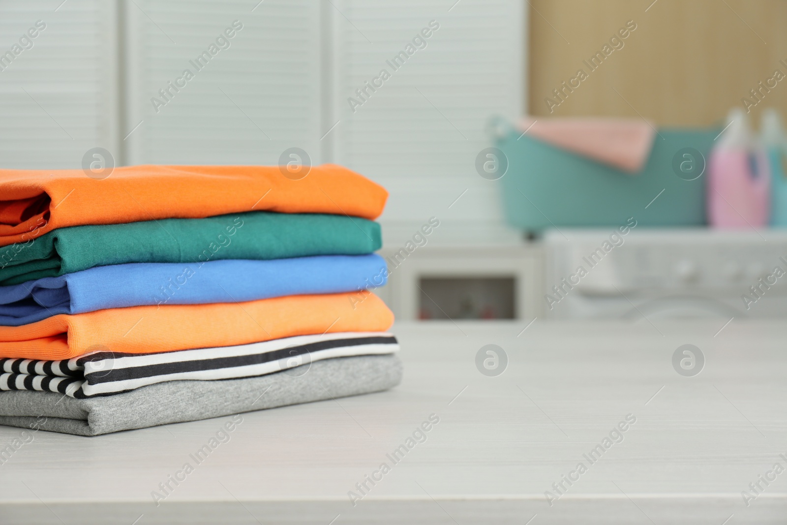 Photo of Fresh laundry on white wooden table in bathroom. Space for text