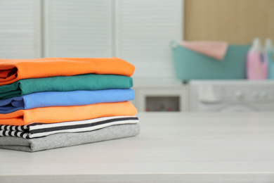 Fresh laundry on white wooden table in bathroom. Space for text