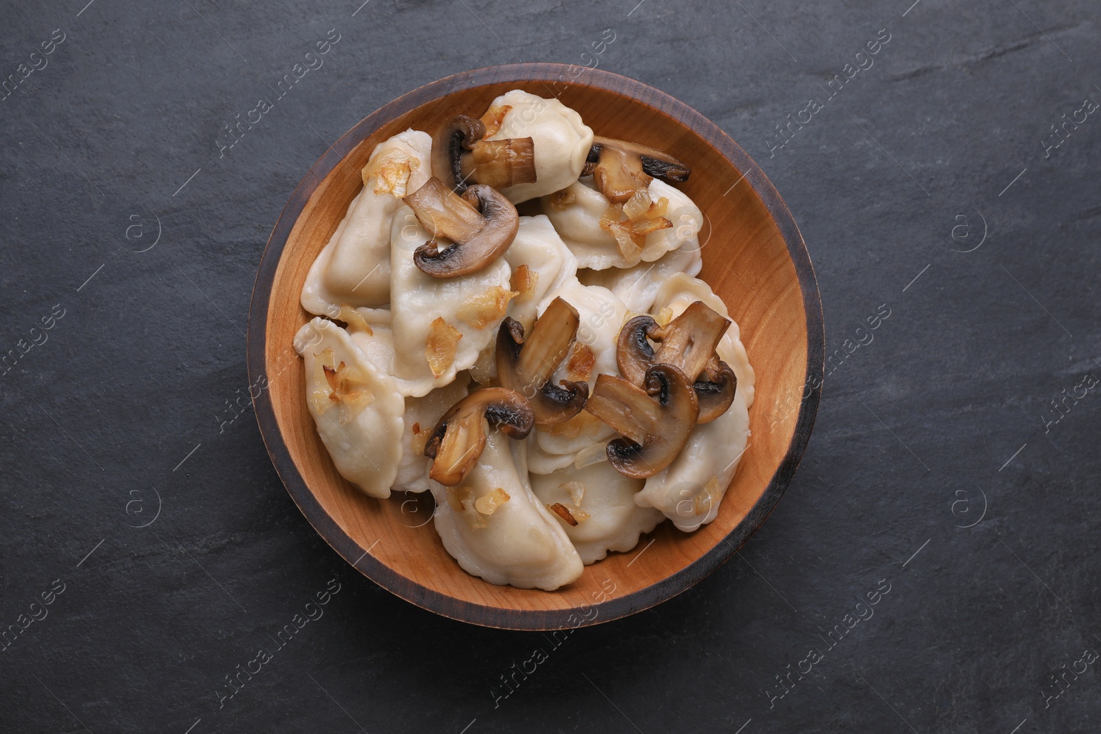 Photo of Delicious dumplings (varenyky) with potatoes, onion and mushrooms on black table, top view