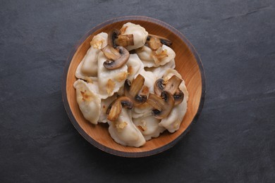 Delicious dumplings (varenyky) with potatoes, onion and mushrooms on black table, top view
