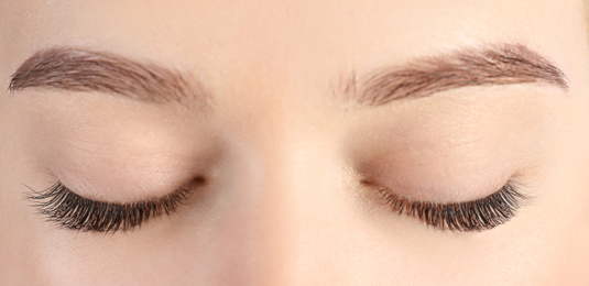 Image of Young woman with beautiful eyelashes after extension procedure, closeup. Banner design