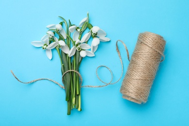 Beautiful snowdrops and twine on light blue background, flat lay