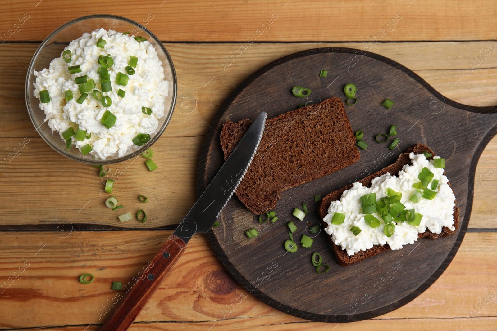 Photo of Bread with cottage cheese and green onion on wooden table, flat lay