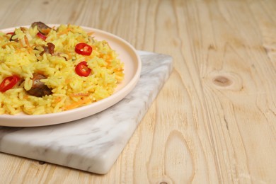 Photo of Delicious pilaf with meat on wooden table. Space for text