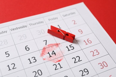 Photo of Calendar with marked Valentine's Day and clothespin on red background, closeup