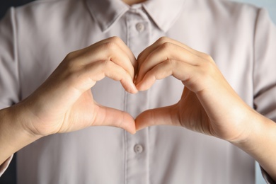 Photo of Woman showing heart sign, closeup. Body language