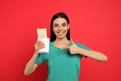 Photo of Happy young woman with delicious shawarma on red background