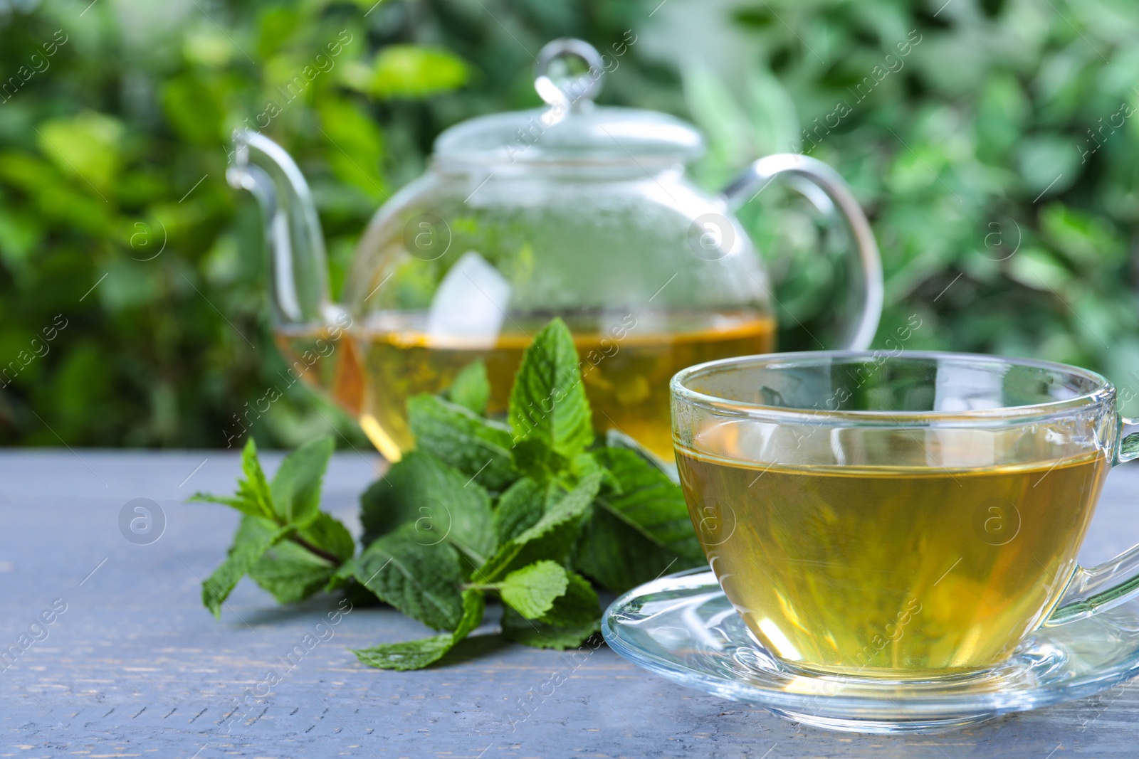 Photo of Fresh green tea with mint leaves on light grey wooden table