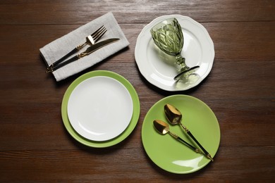 Photo of Beautiful ceramic plates, glass and cutlery on wooden table, flat lay