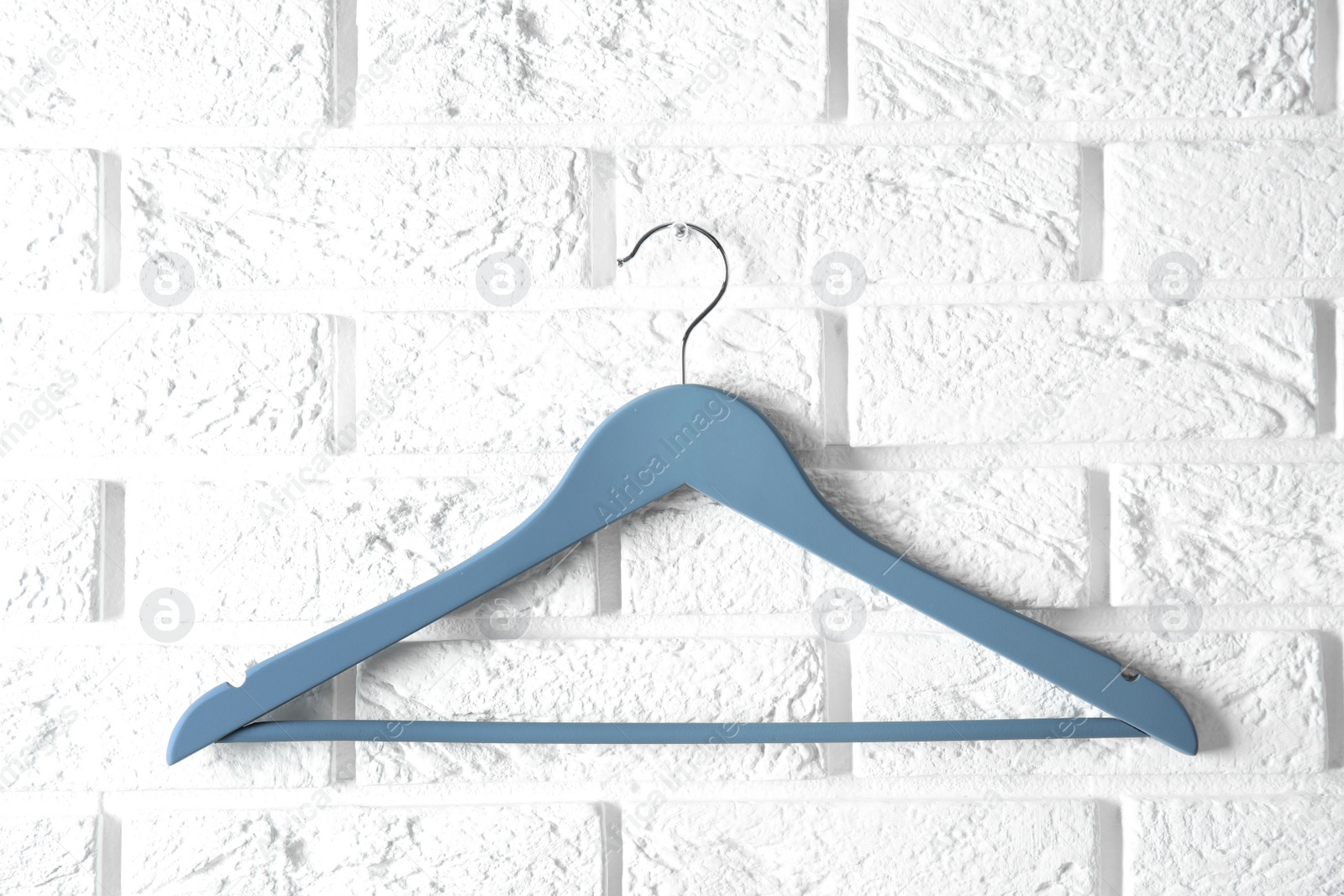 Photo of Empty clothes hanger on brick wall. Wardrobe accessory