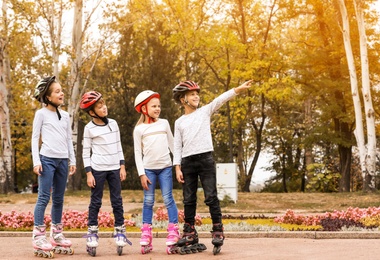 Photo of Happy children wearing roller skates in autumn park. Space for text