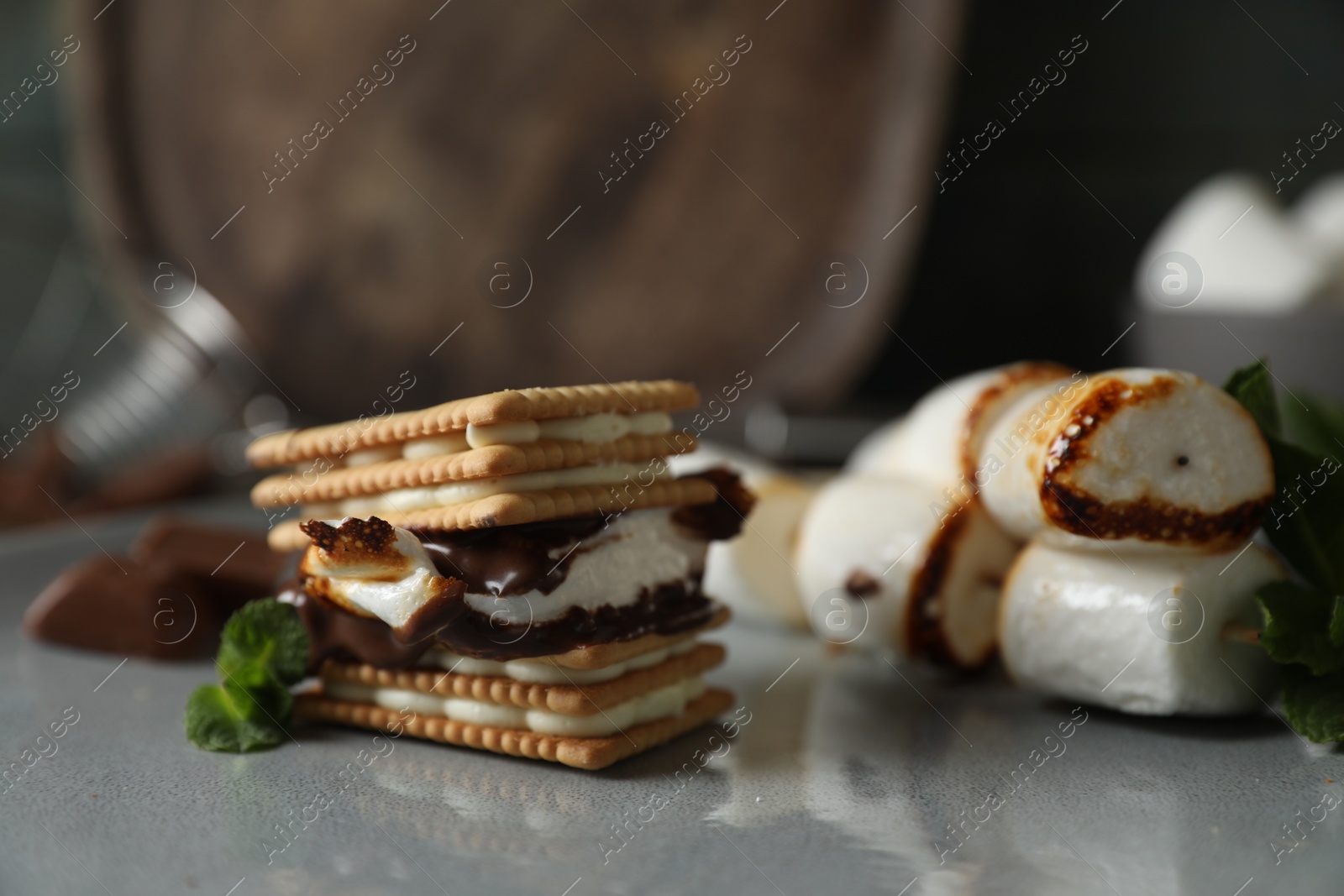 Photo of Delicious marshmallow sandwiches with crackers and chocolate on grey plate, closeup