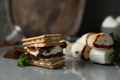 Delicious marshmallow sandwiches with crackers and chocolate on grey plate, closeup