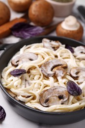 Delicious pasta with mushrooms in pan on table, closeup