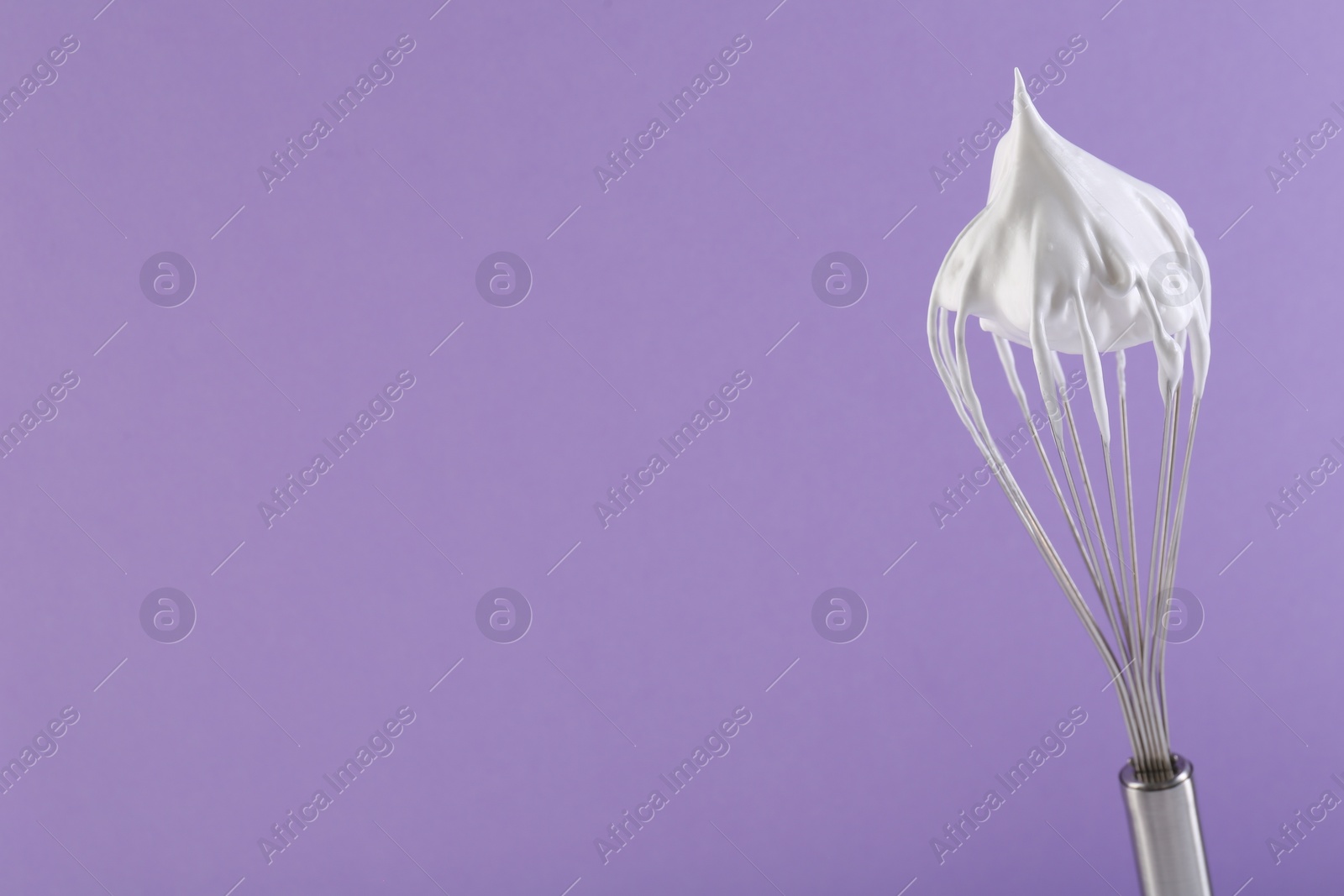 Photo of Whisk with whipped cream on violet background. Space for text