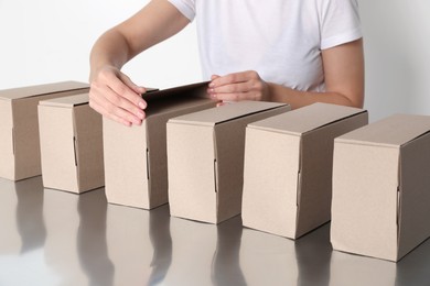 Photo of Woman folding cardboard boxes at table, closeup. Production line
