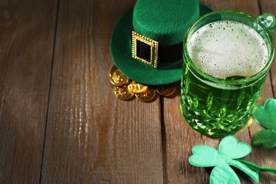 Photo of St. Patrick's day party. Green beer, leprechaun hat, gold and decorative clover leaves on wooden table. Space for text