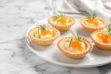 Delicious canapes with red caviar on white marble table, closeup