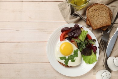 Delicious breakfast with fried egg and salad served on light wooden table, flat lay. Space for text