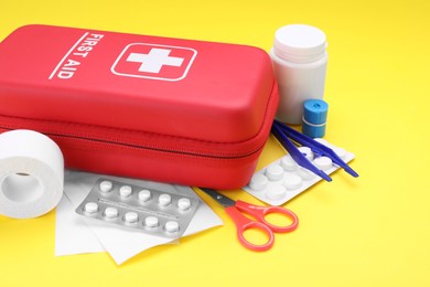 Photo of First aid kit on yellow background, closeup