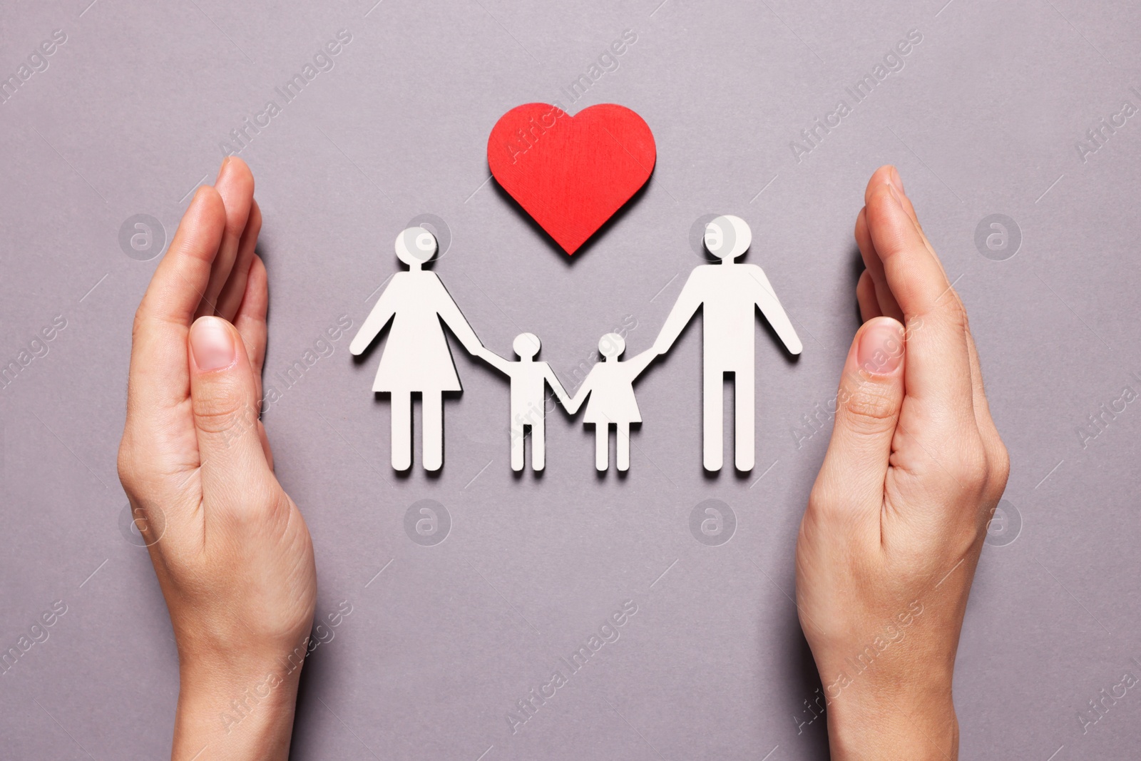 Photo of Woman protecting figures of family and heart on lilac background, top view. Insurance concept