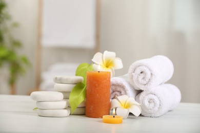 Composition with different spa products and plumeria flowers on white marble table indoors