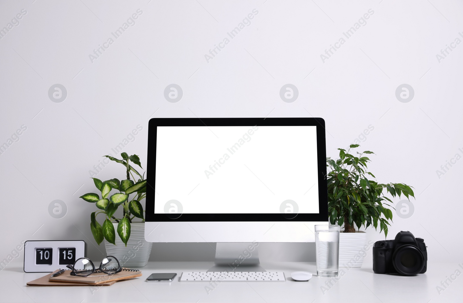 Photo of Comfortable workplace with modern computer on table near white wall. Space for text