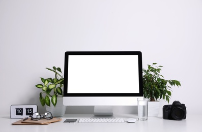 Photo of Comfortable workplace with modern computer on table near white wall. Space for text