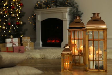 Christmas lanterns with burning candles in decorated living room. Space for text