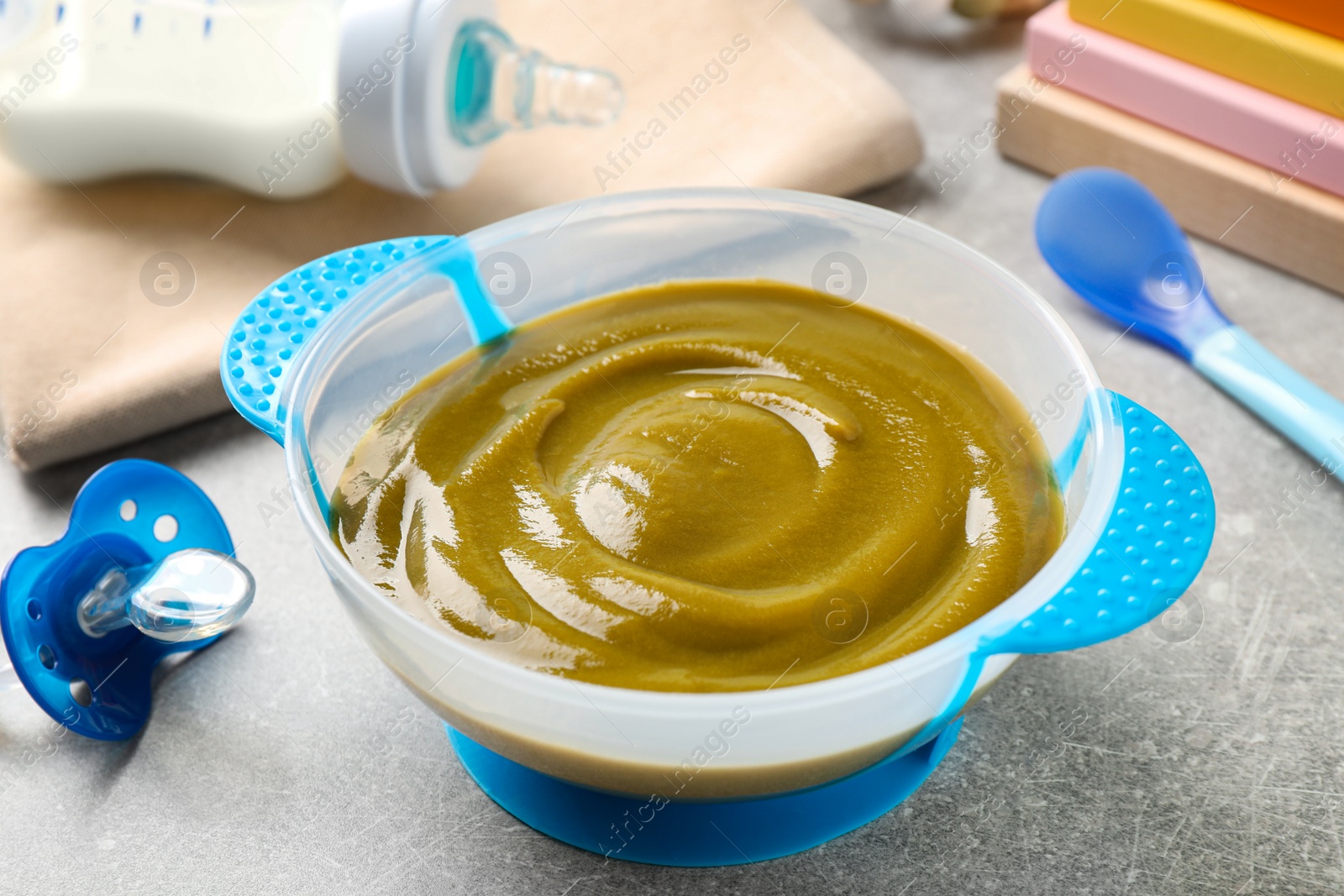 Photo of Bowl of healthy baby food on grey table