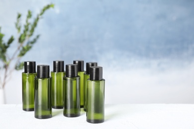 Photo of Mini bottles with cosmetic products on white table against blue background. Space for text