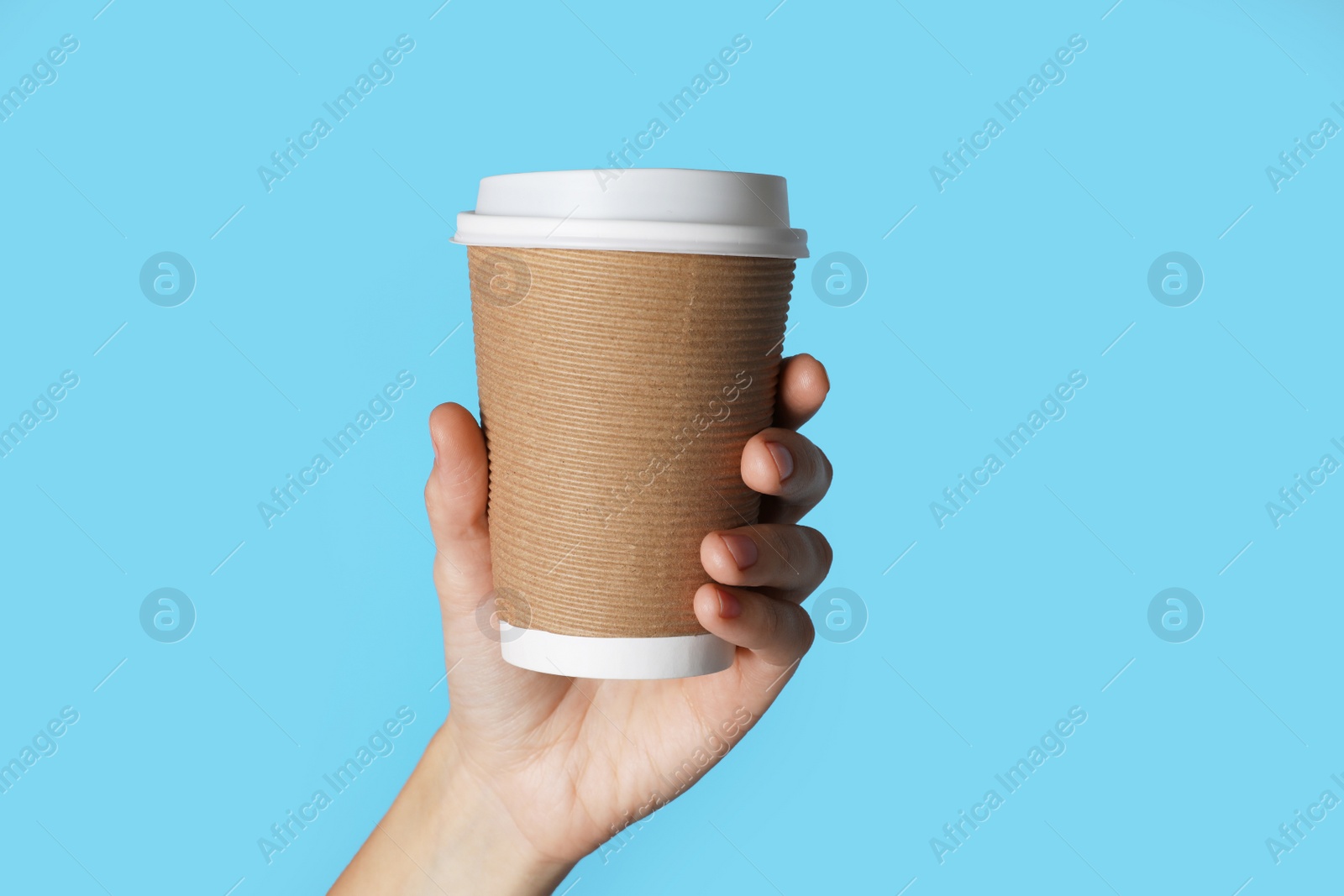 Photo of Woman holding takeaway paper coffee cup on blue background, closeup