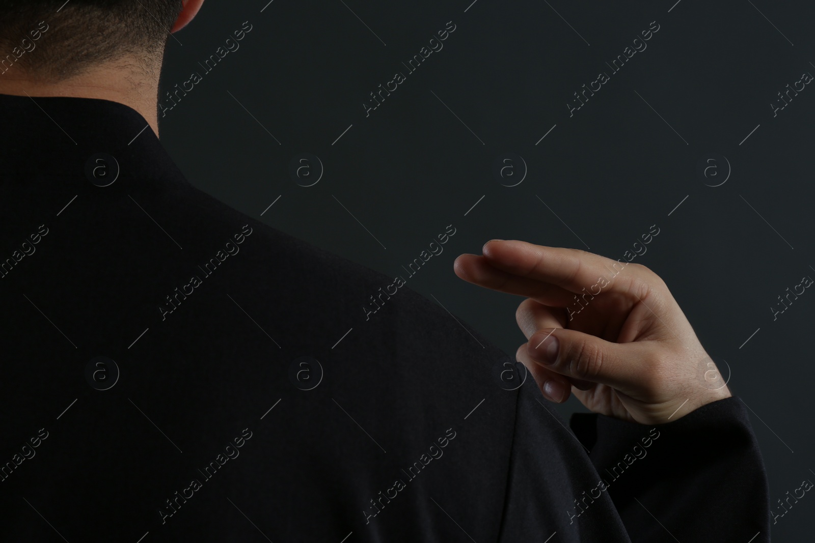 Photo of Priest making cross sign on black background, closeup