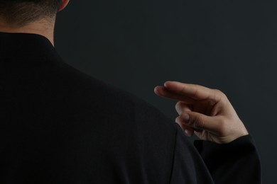 Photo of Priest making cross sign on black background, closeup